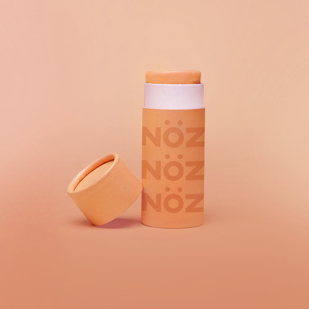 A stick of Noz’s reef-safe sunscreen in orange with the cap off